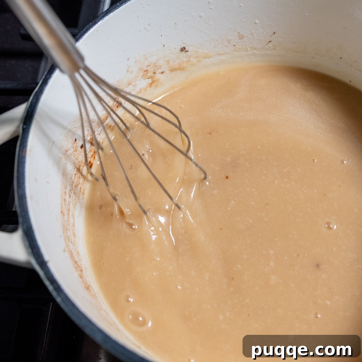 Melted butter being whisked with gluten-free flour in a pot to form a roux.
