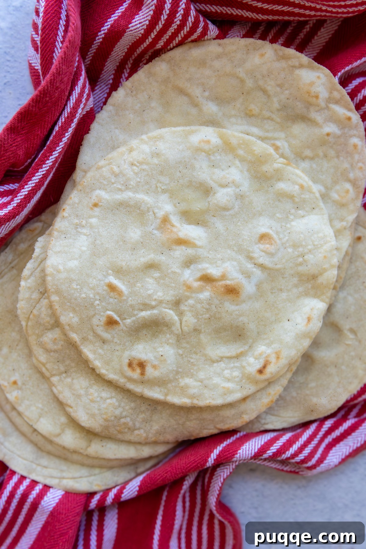 Overhead shot of stack of tortillas laying flat on a striped towel.