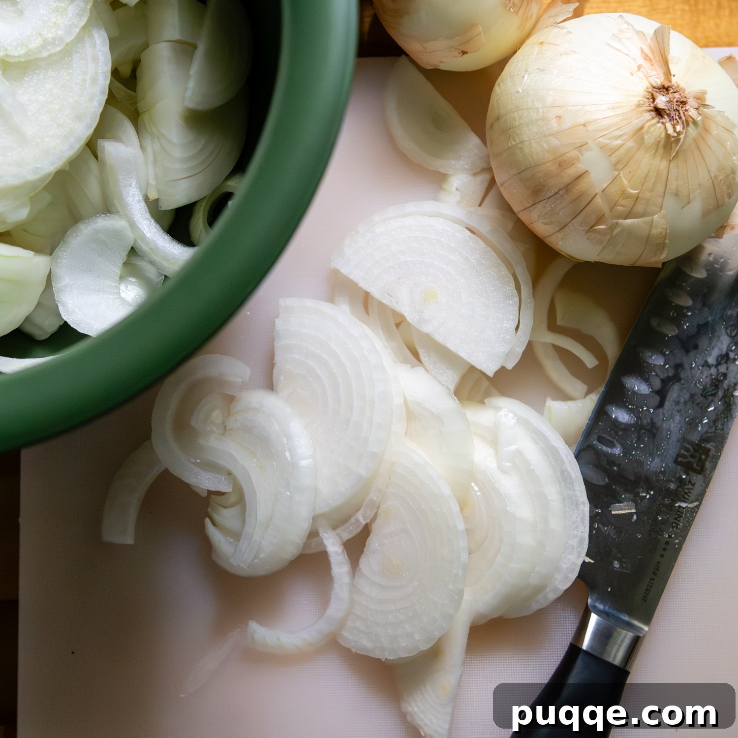 Easy Gourmet Gluten-Free French Onion Soup 3 Green bowl filled with thinly sliced sweet onions, with a whole onion beside it, ready for caramelization.