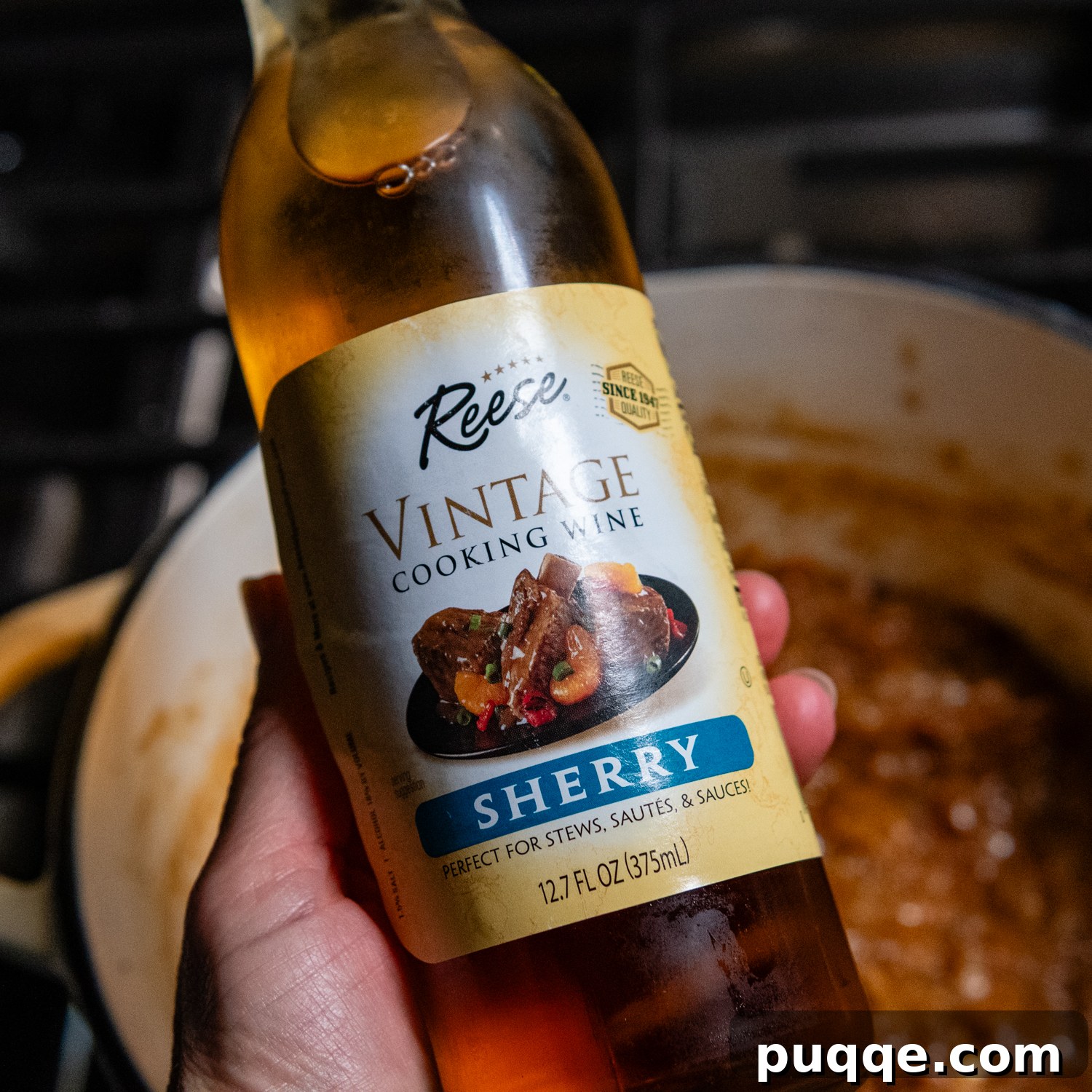 Easy Gourmet Gluten-Free French Onion Soup 7 A hand holding a bottle of dry cooking sherry, highlighting this essential ingredient for French onion soup.