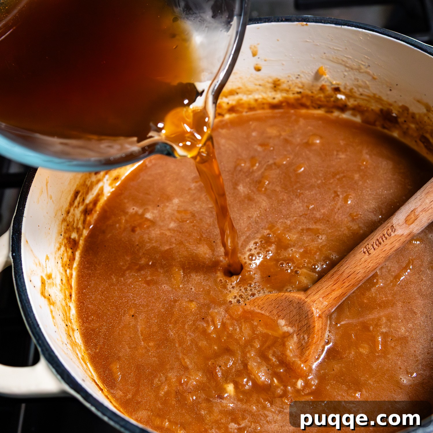 Easy Gourmet Gluten-Free French Onion Soup 8 Rich gluten-free beef broth being poured into a pot of perfectly cooked and seasoned caramelized onions, forming the base of the French onion soup.