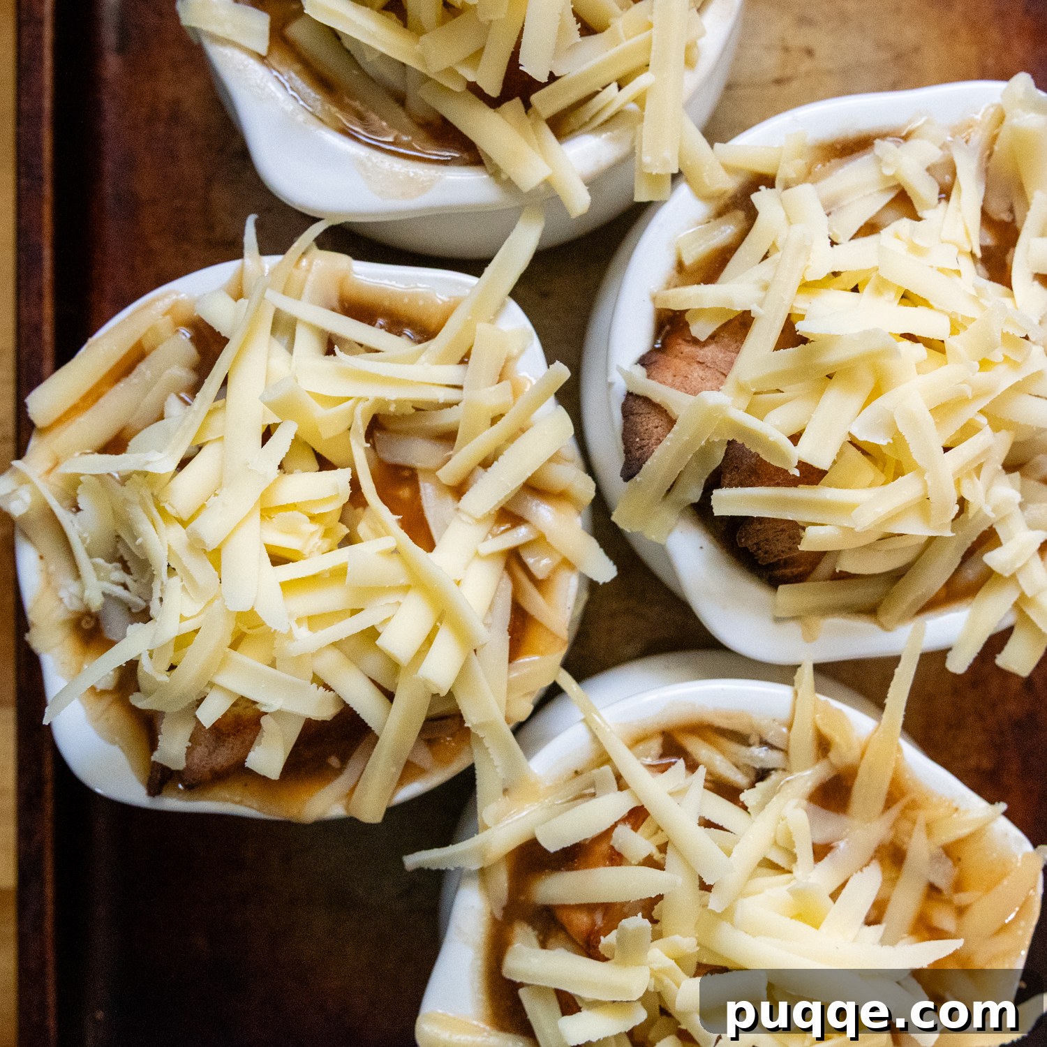 Easy Gourmet Gluten-Free French Onion Soup 10 Individual soup crocks filled with rich French onion soup, generously topped with freshly grated Gruyere cheese and toasted gluten-free bread, ready for broiling.