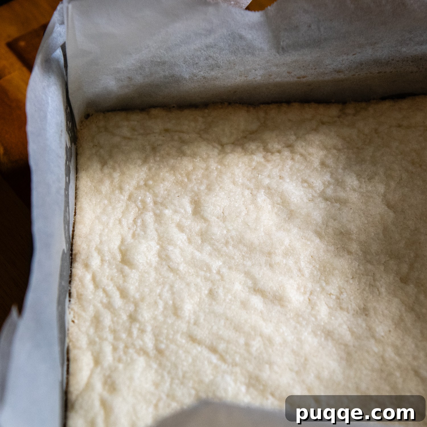 The baked shortbread crust, golden and firm, resting in the parchment-lined metal pan.