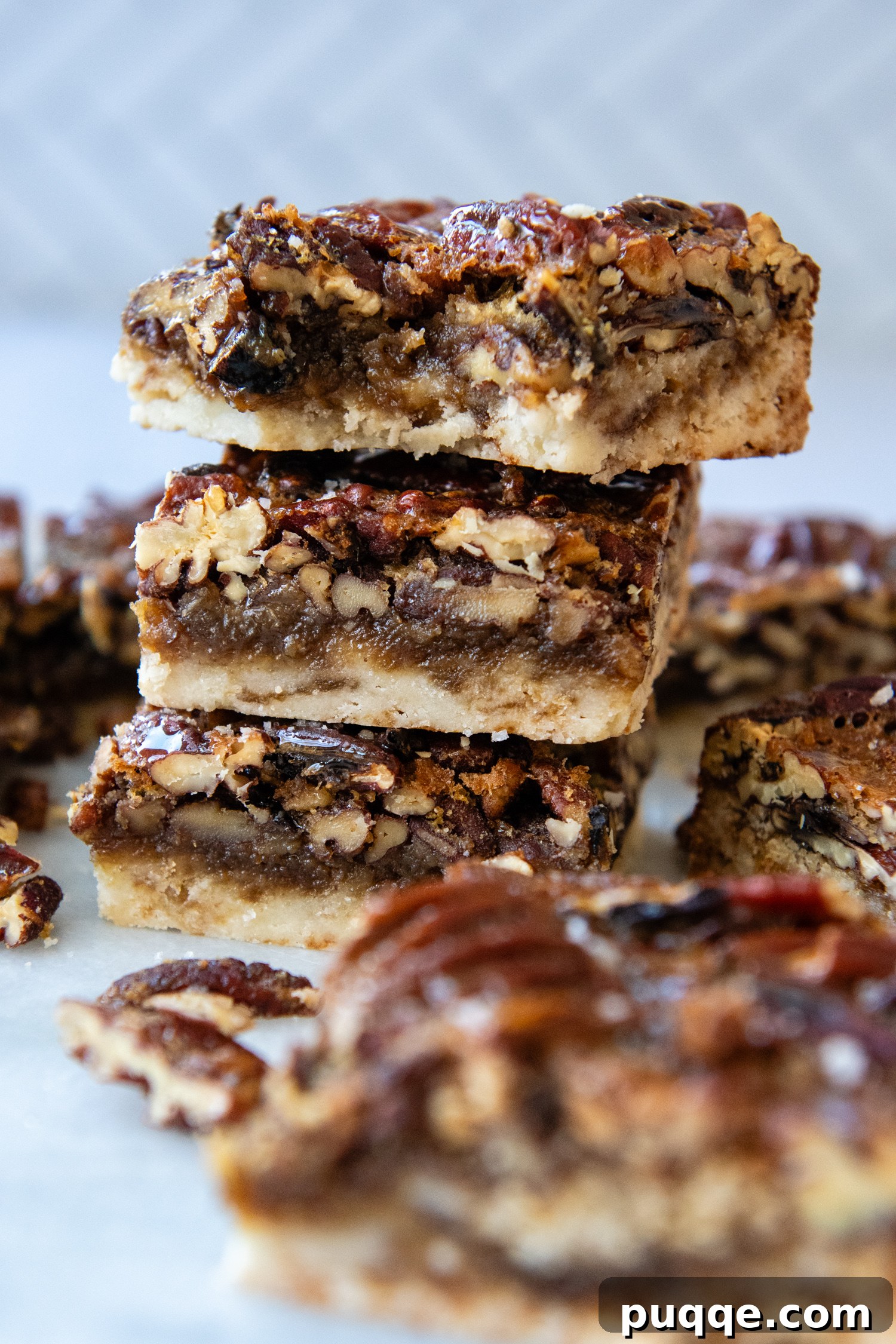 Close-up shot showing the distinct layers of the gluten-free pecan pie bars: the golden shortbread crust, the rich pecan filling, and the glistening topping.