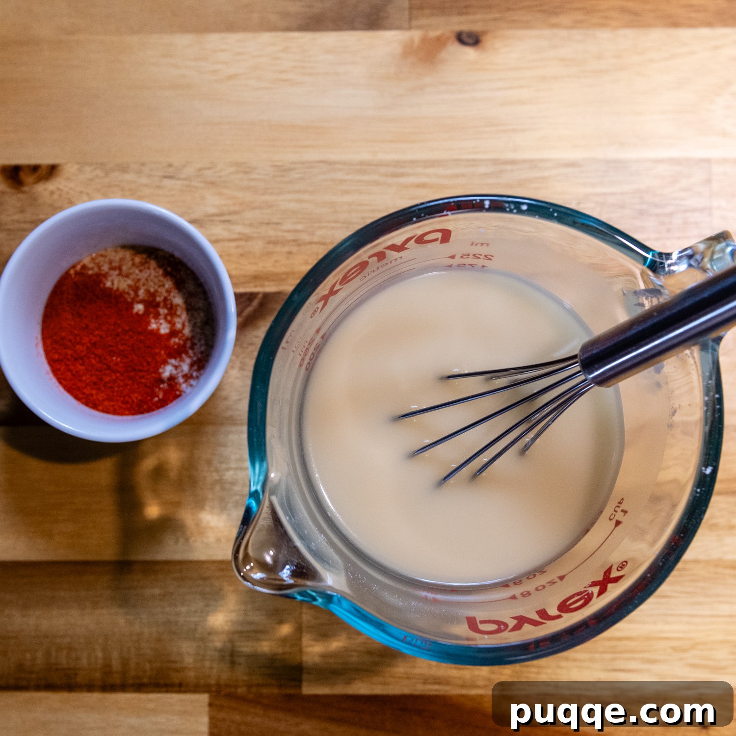 Ultimate Cheesy Gluten-Free Hash Brown Bake from Scratch 3 Liquid ingredients, chicken broth and cornstarch, being whisked together in a glass measuring cup, preparing for the gluten-free cream sauce.