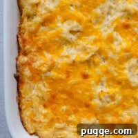 Cheesy gluten free hash brown casserole in a white baking dish.