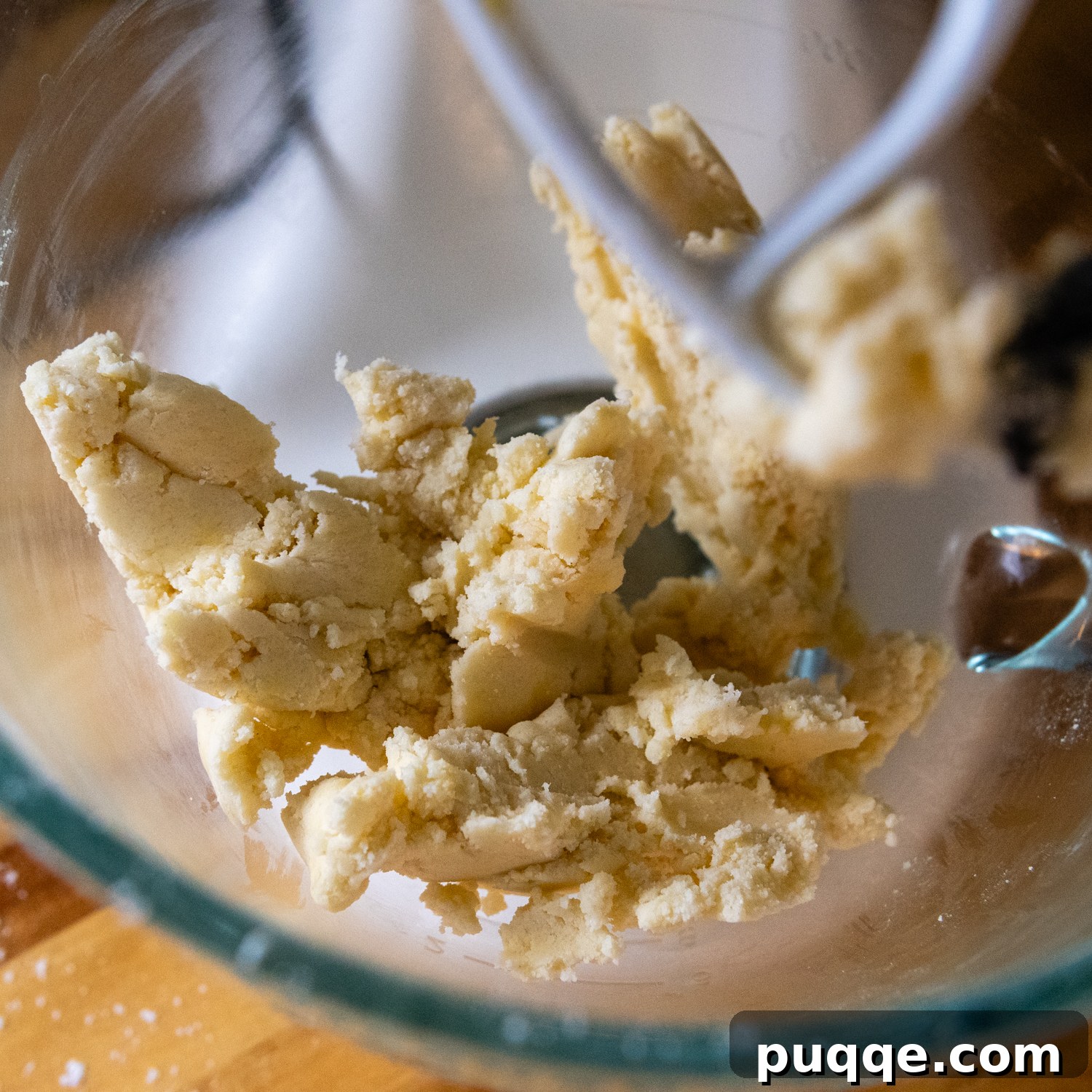 Effortless Gluten-Free Millionaire Bars 5 Shortbread mixture in a glass mixing bowl after adding egg yolk, forming a soft dough.