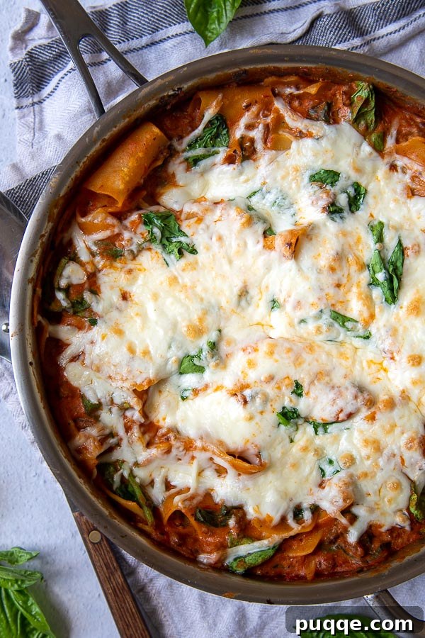 One-Pan Ricotta Spinach Lasagna 4 An overhead shot of skillet lasagna in a gleaming stainless steel pan, garnished with fresh basil, ready to be served.