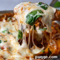 A spatula pulling up a serving of skillet lasagna with cheese dripping down