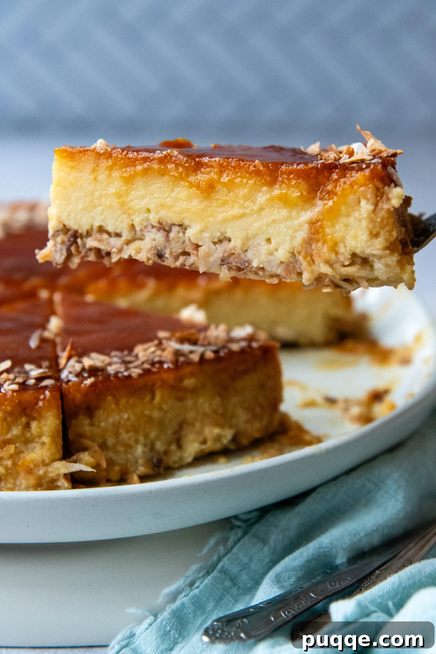 Double Coconut Flan Delight 2 A piece of coconut flan being lifted off of a white plate by a fork, showcasing its layers of caramel, custard, and toasted coconut.