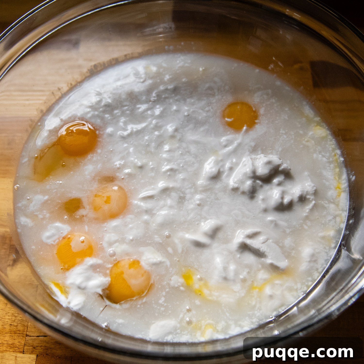 Double Coconut Flan Delight 5 Liquid flan ingredients, a smooth mixture of coconut milk, condensed milk, and eggs, in a glass bowl.