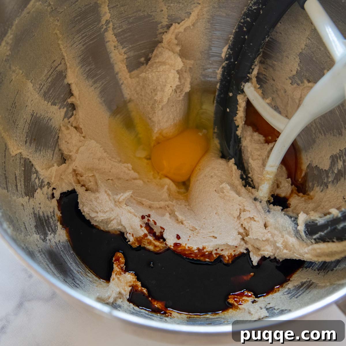 Cookie dough being mixed with egg and molasses, showing the wet ingredients combining.