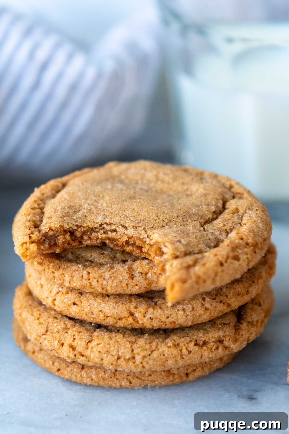 A tempting stack of gluten-free ginger cookies, with one having a delicious bite taken out.