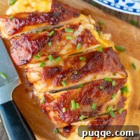 Overhead shot of two BBQ bacon wrapped chicken breasts, garnished with chives.
