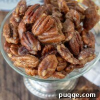 An overhead shot of candied pecans presented in an antique silver bowl, ready for serving.