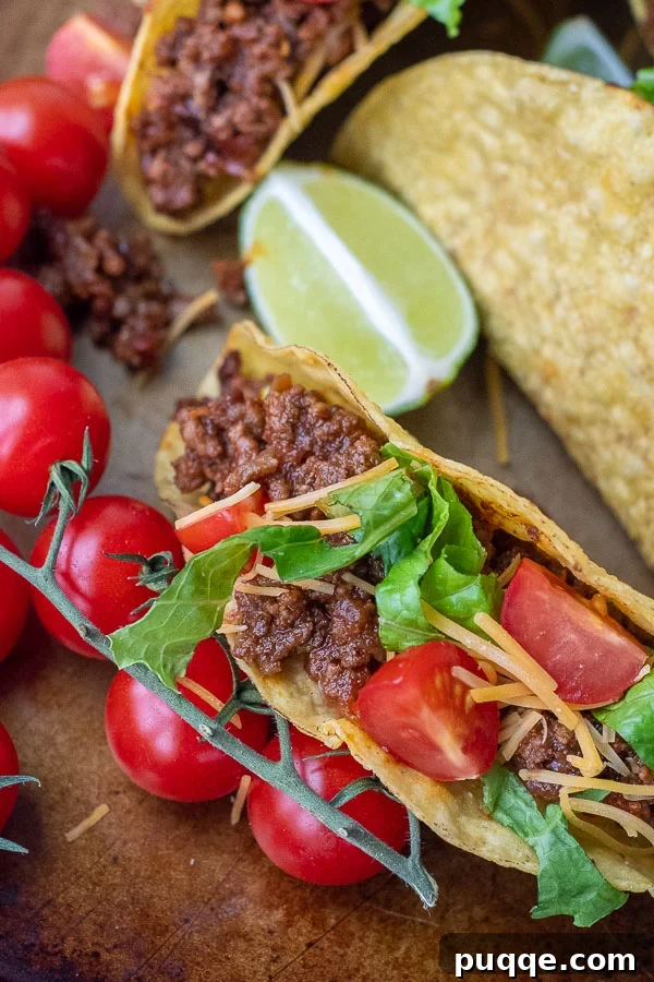 Close up of a savory beef taco with fresh tomatoes, shredded cheese, and crisp lettuce