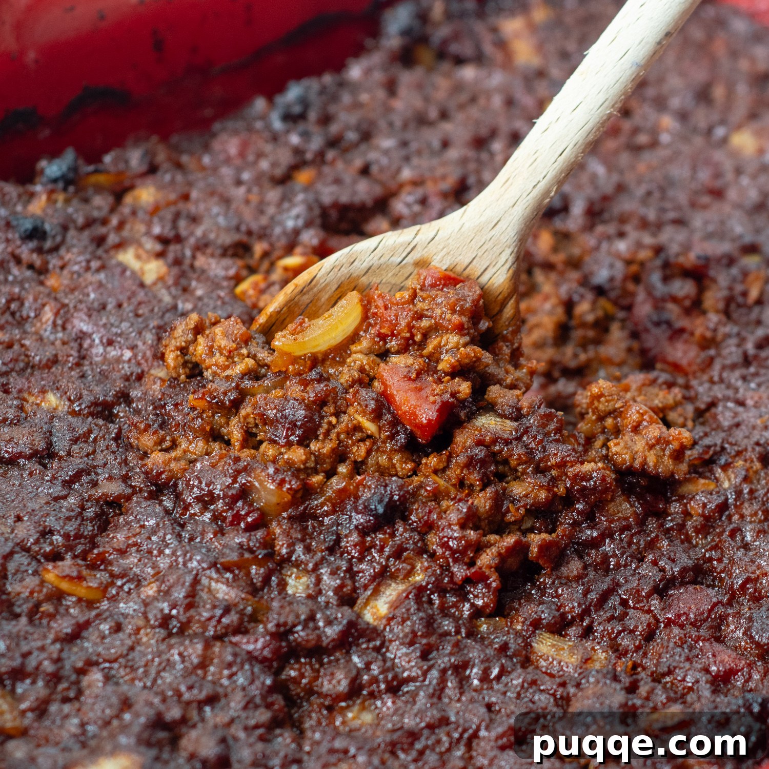 The taco meat baking in a pan, with a wooden spoon lifting a portion, showcasing the developing crust