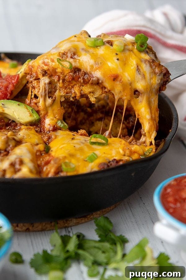 Authentic Gluten-Free Tamale Pie Made From Scratch 2 A delectable slice of Tamale Pie being served from a cast iron skillet, showcasing layers of savory beef, golden cornbread, and melted cheese.