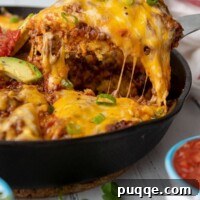 A slice of tamale pie being lifted out of a cast iron skillet with cheese stringing off