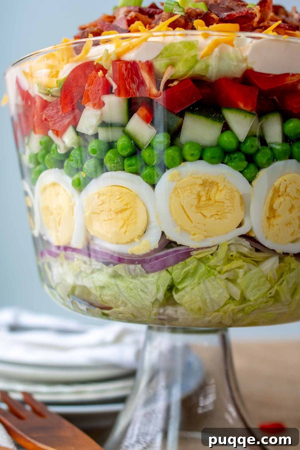 close up of 7 layer salad layers in a glass trifle bowl