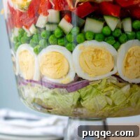 close up of 7 layer salad layers in a glass trifle bowl