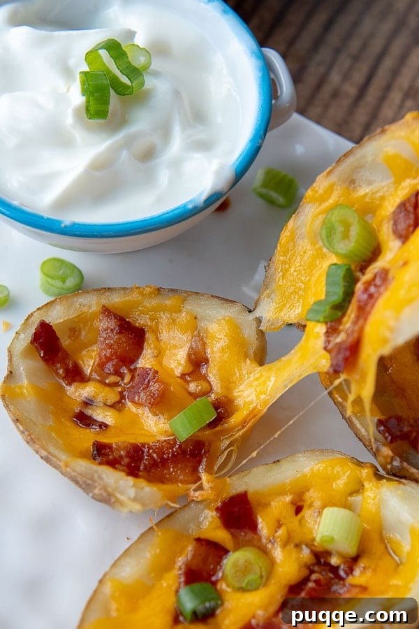 A cheesy potato skin being gently pulled apart on a clean white plate, showcasing the melted cheese and crispy edges.