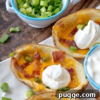 A close-up of a loaded potato skin with a dollop of sour cream on top, ready to be served.