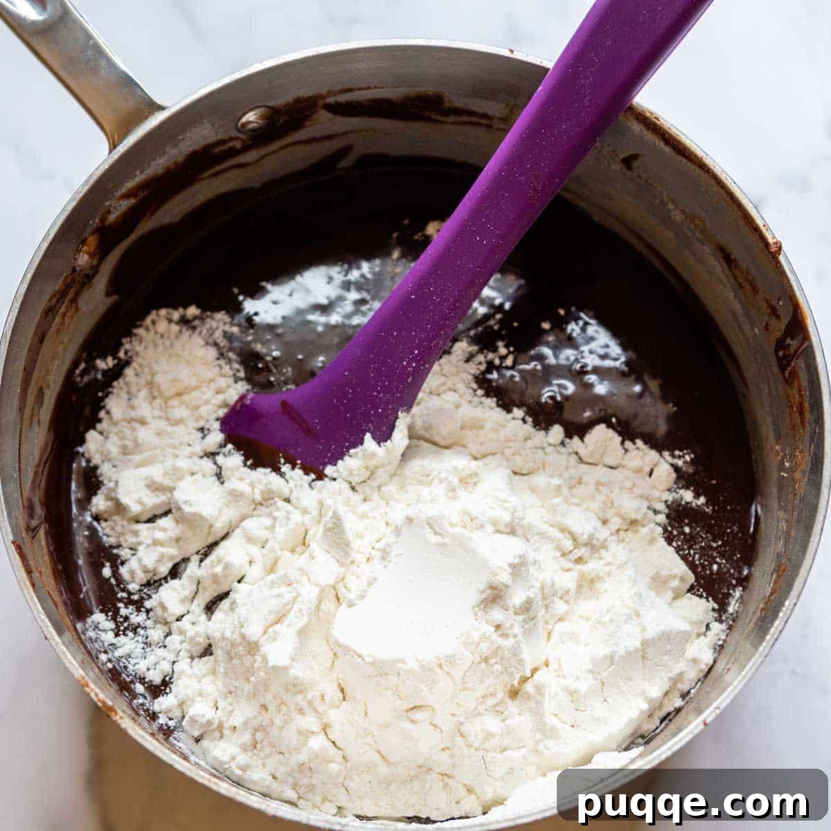 Perfectly Fudgy Gluten-Free Brownies with Crackly Tops 7 Gluten-free flour being carefully stirred into the rich chocolate brownie batter in a saucepan, ensuring a smooth, well-combined mixture.