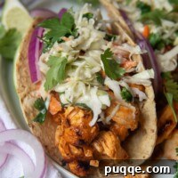 a close up of buffalo chicken tacos with a blue cheese slaw on top with sliced red onions on plate