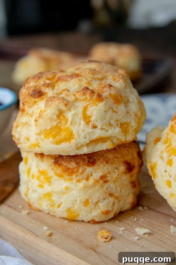 Melt-in-Your-Mouth Gluten-Free Cheddar Scones 2 A stack of two perfectly golden-brown gluten-free cheese scones on a rustic wooden cutting board, ready to be enjoyed.