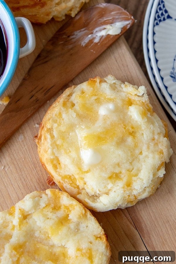 Melt-in-Your-Mouth Gluten-Free Cheddar Scones 3 A freshly baked gluten-free cheese scone sliced open, revealing its tender, cheesy interior, with butter ready to be spread.
