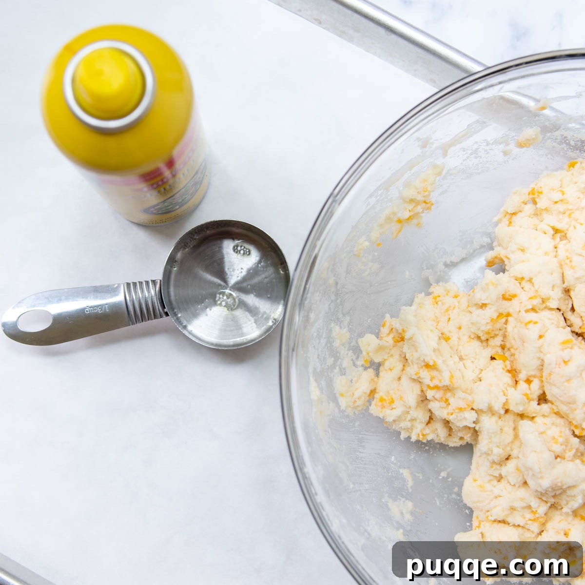 Melt-in-Your-Mouth Gluten-Free Cheddar Scones 7 Greased measuring cup with scone dough, ready to be dropped onto a baking sheet.