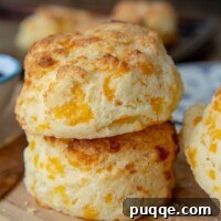 Melt-in-Your-Mouth Gluten-Free Cheddar Scones 10 A stack of 2 gluten free cheese scones on a wood cutting board