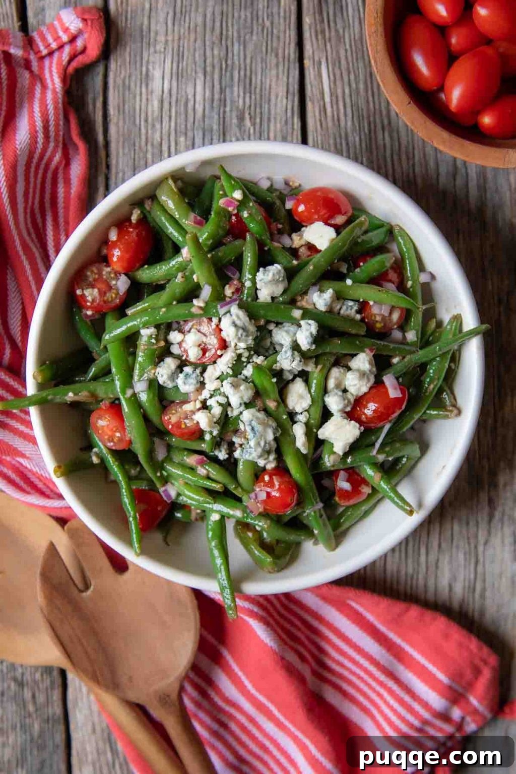 Tangy Green Bean Salad 5 overhead of green bean salad in a white bowl with a red towel and serving tongs