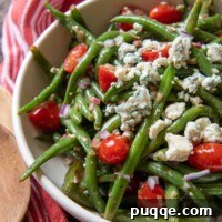 a close up of a serving bowl of beans, blue cheese and tomatoes