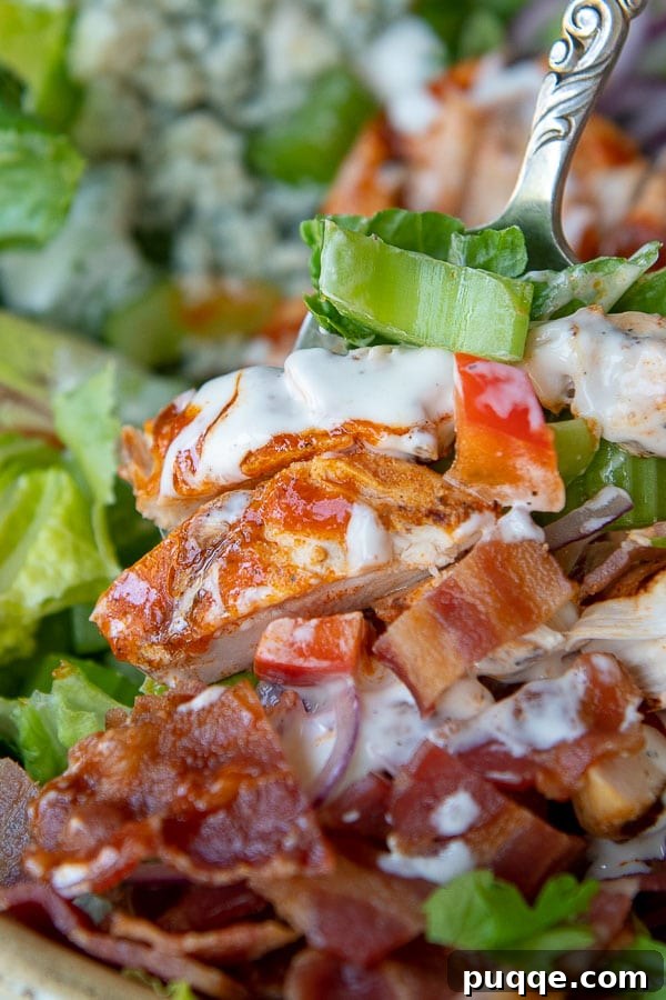 A close-up shot of buffalo chicken pieces tossed with ranch dressing, sitting atop the assembled salad.