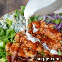 Ranch dressing being poured over buffalo chicken salad