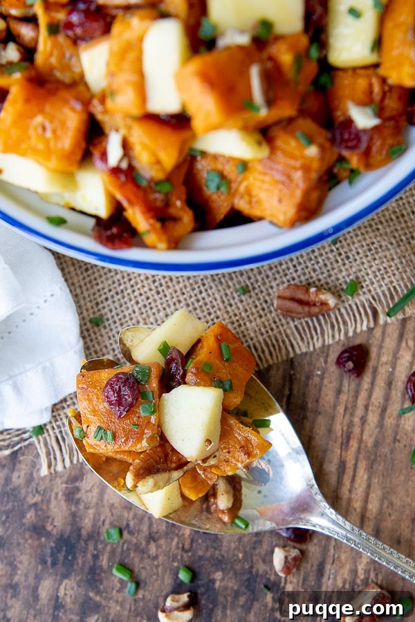 Orchard Sweet Potato Salad 6 An antique silver spoon resting on a rustic wooden table, gracefully holding a scoop of the roasted sweet potato salad, emphasizing its delicious appeal and rich texture.