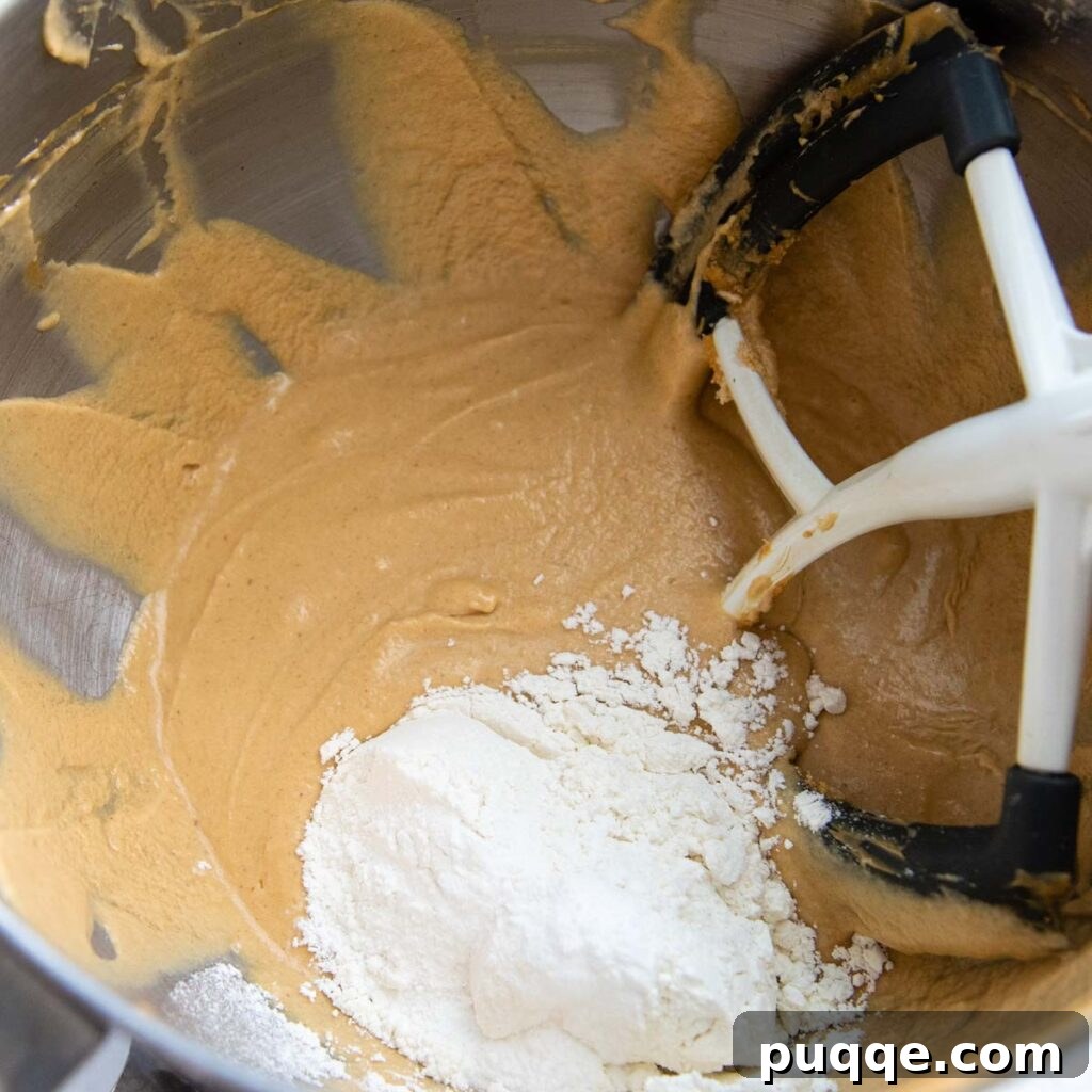 Effortless Gluten-Free Peanut Butter Quick Bread 4 Gluten-free flour being added to the quick bread batter in a mixing bowl.