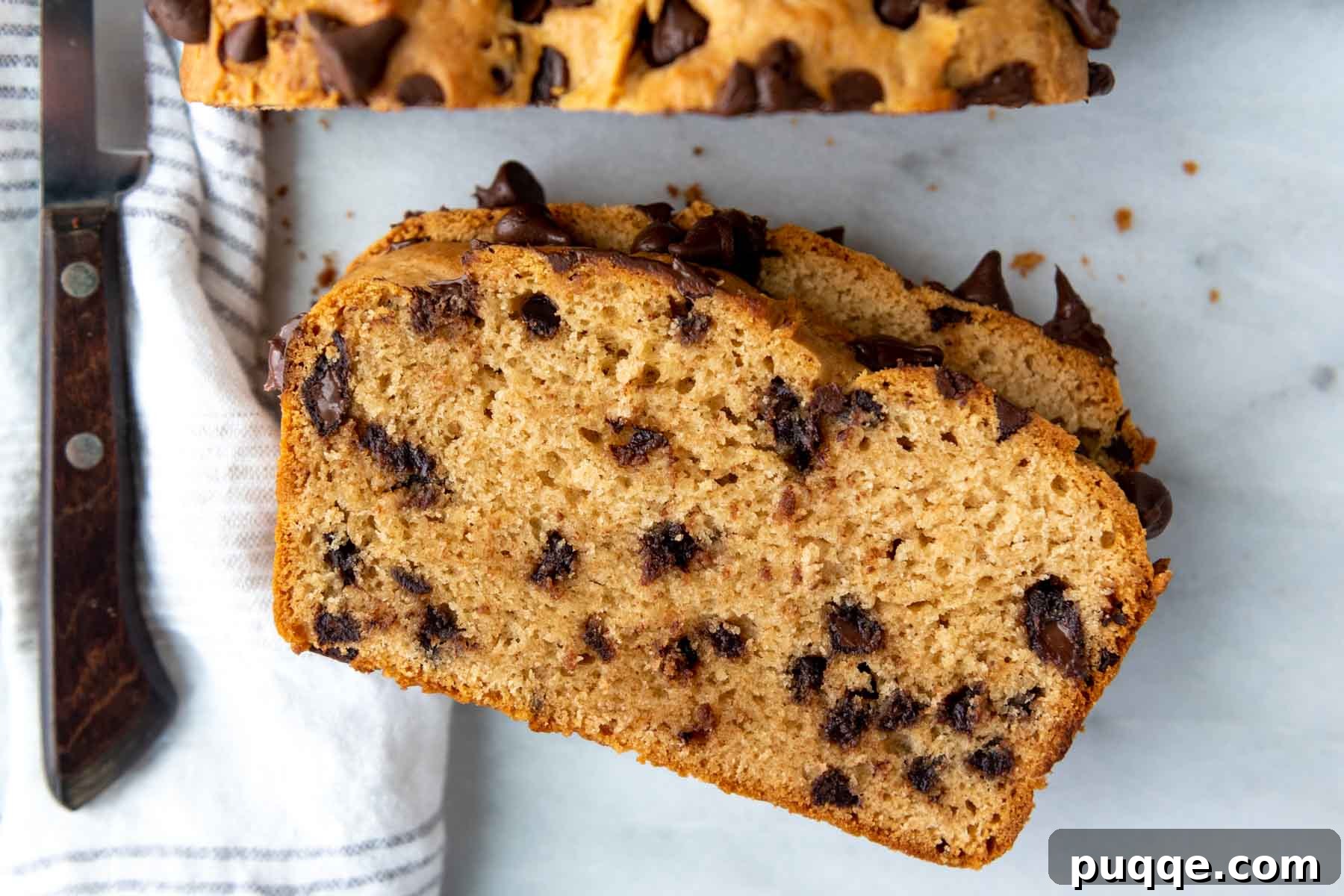 Effortless Gluten-Free Peanut Butter Quick Bread 7 A perfectly baked slice of gluten-free peanut butter bread with chocolate chips, presented face-up with a knife nearby, ready for enjoyment.