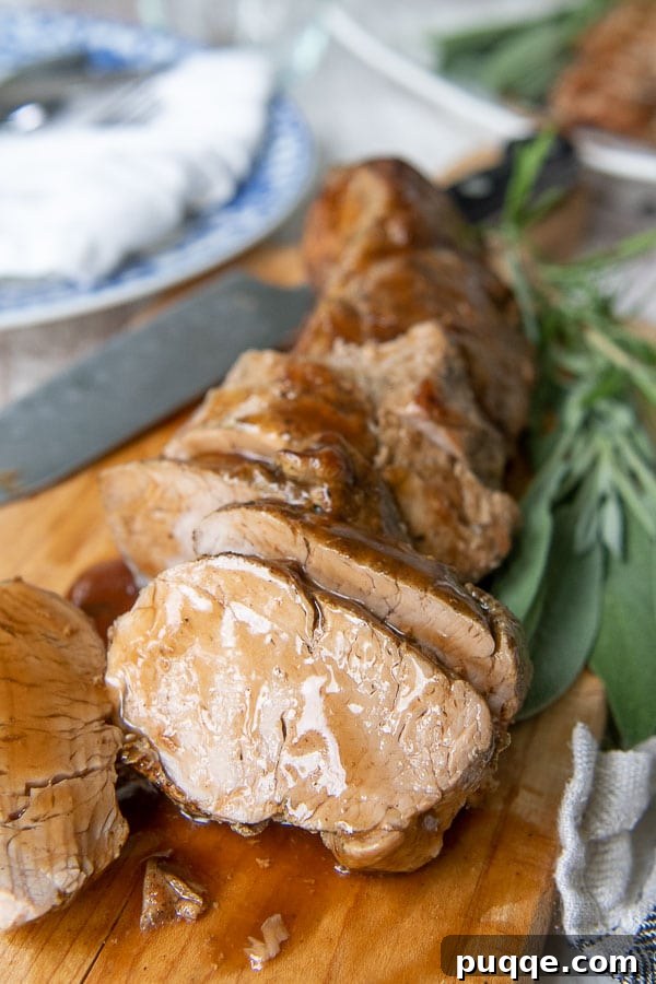 cut pieces of pork tenderloin on a wooden cutting board with sauce drizzled over