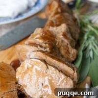 cut pieces of pork tenderloin on a wooden cutting board with sauce drizzled over