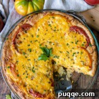 an overhead shot of tomato pie with a slice cut out and fresh tomatoes around it