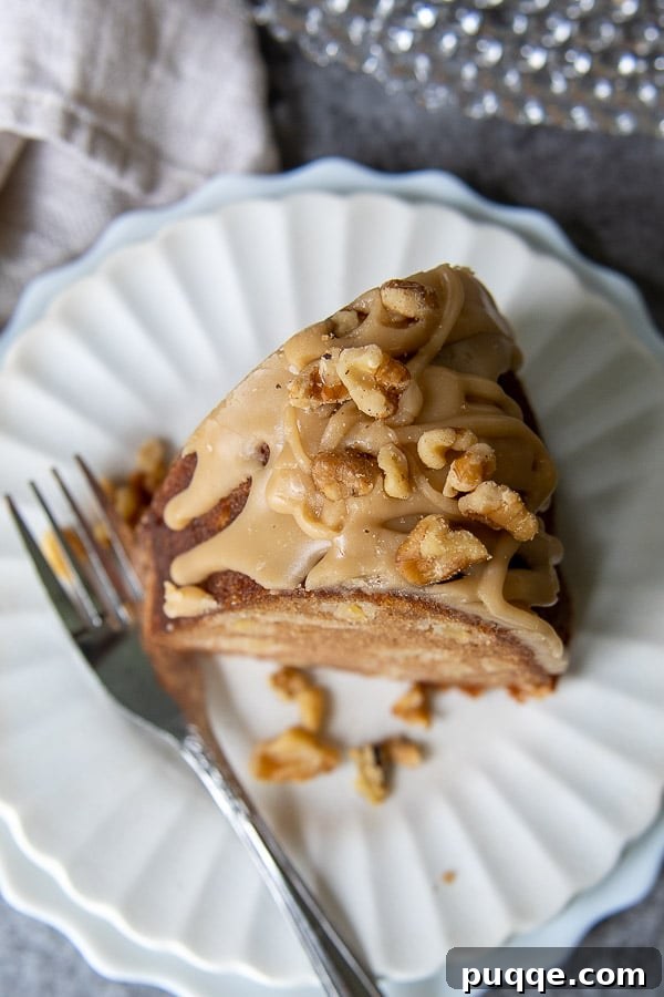 Brown Sugar Praline Glazed Apple Cake 14 An overhead shot of a slice of moist apple cake on a pristine white plate, with a fork resting gracefully beside it, inviting a delicious tasting.