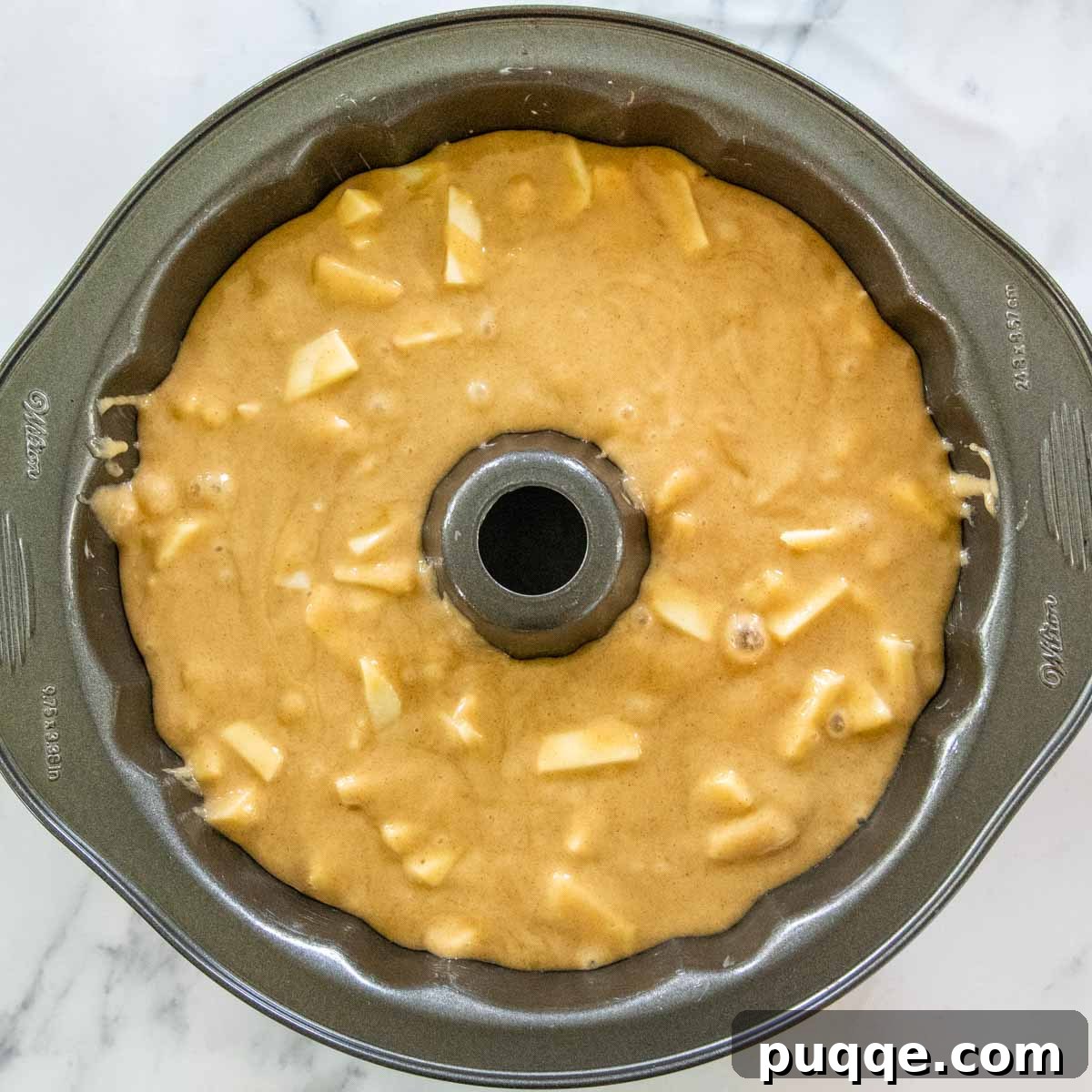Brown Sugar Praline Glazed Apple Cake 8 Unbaked apple cake batter carefully poured into a greased bundt pan, ready for baking.