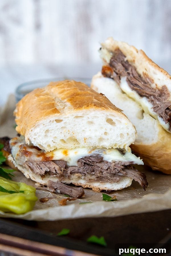 A perfectly cut French Dip sandwich arranged on a baking sheet, showcasing its melted cheese and rich beef filling
