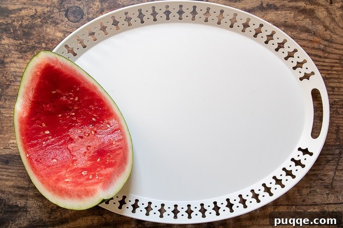 The first step in creating a dessert plate involves strategically placing the largest item, such as a hollowed-out watermelon, to anchor the design.