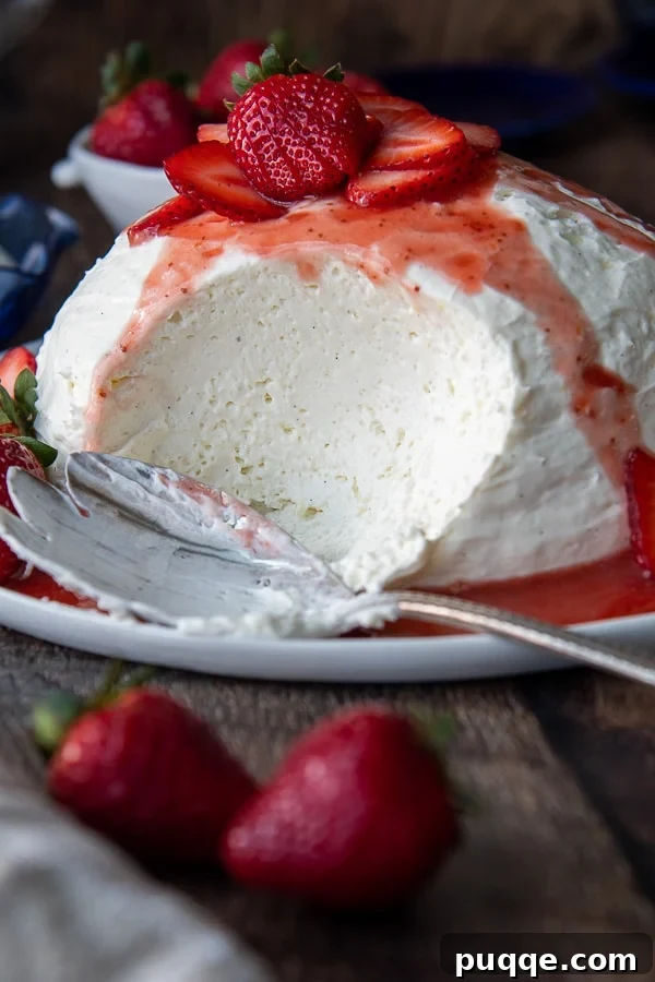 Silky Coeur a la Creme with Vibrant Strawberries 2 A beautifully presented Coeur à la Crème with a generous scoop removed, surrounded by fresh strawberries and a drizzle of strawberry sauce on a white serving platter.