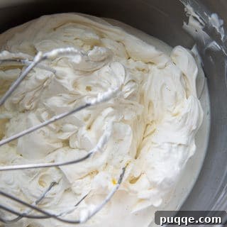 Showing heavy cream, vanilla, and lemon zest added to the cream cheese mixture.