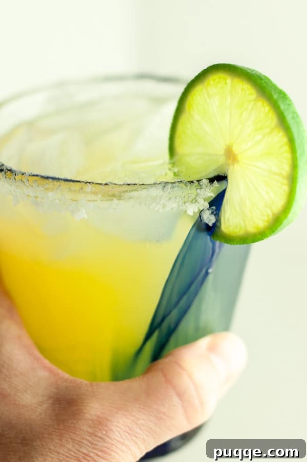 Freshly Crafted Lighter Margarita Recipe 4 a hand holding up a glass of skinny margarita